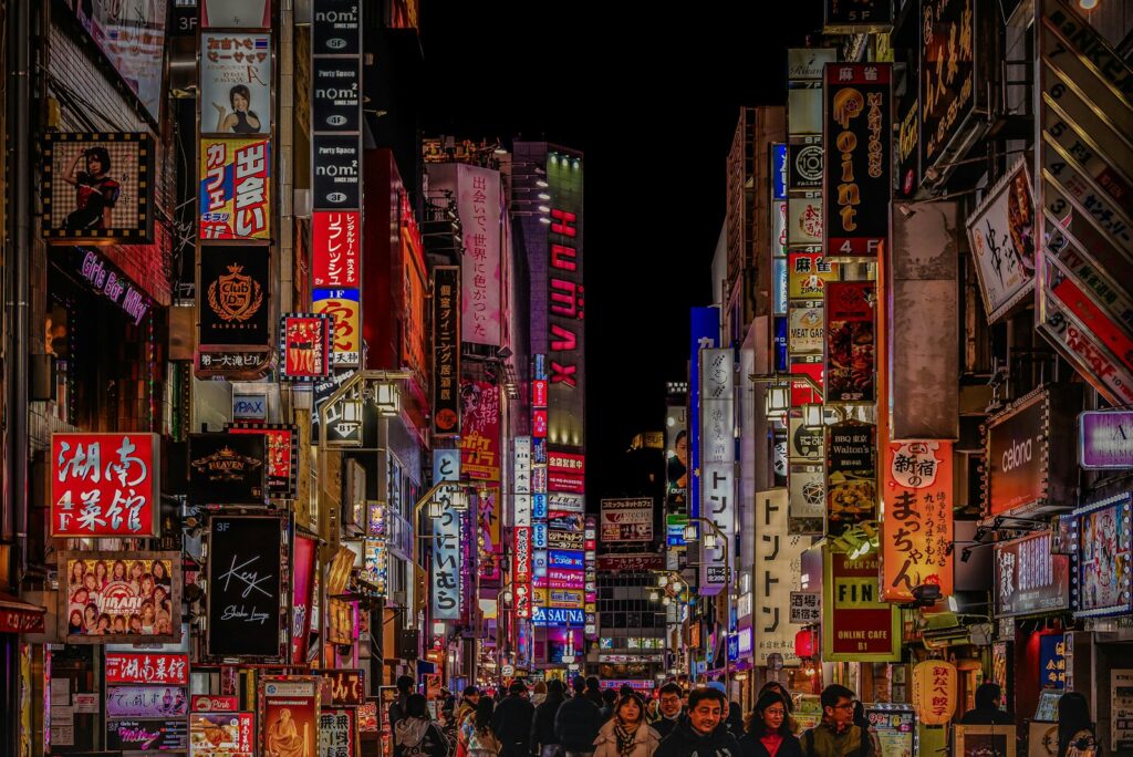 Neon signs above a busy street in Shinjuku, Tokyo at night