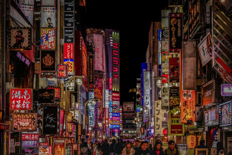 Neon signs above a busy street in Shinjuku, Tokyo at night