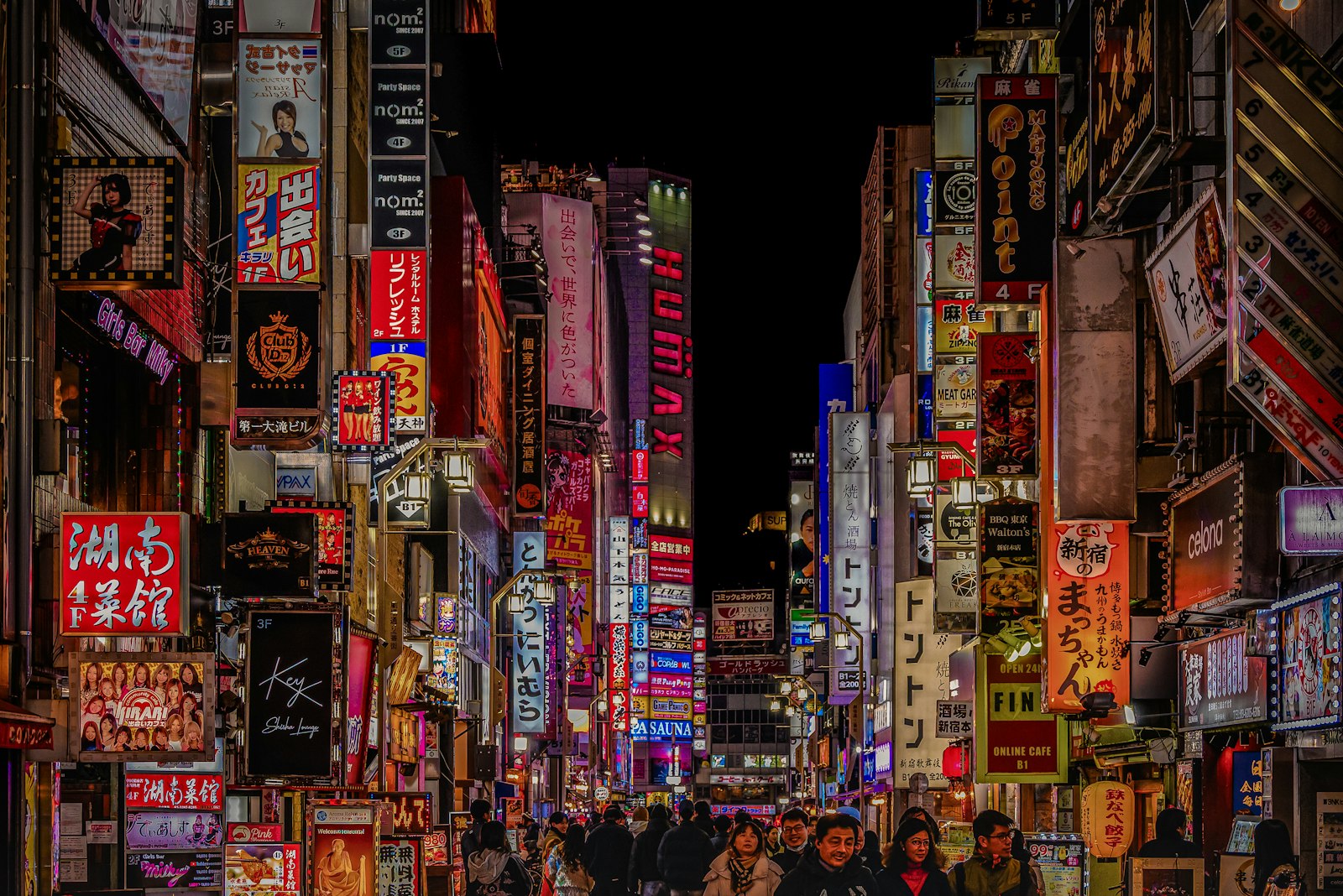 Neon signs above a busy street in Shinjuku, Tokyo at night