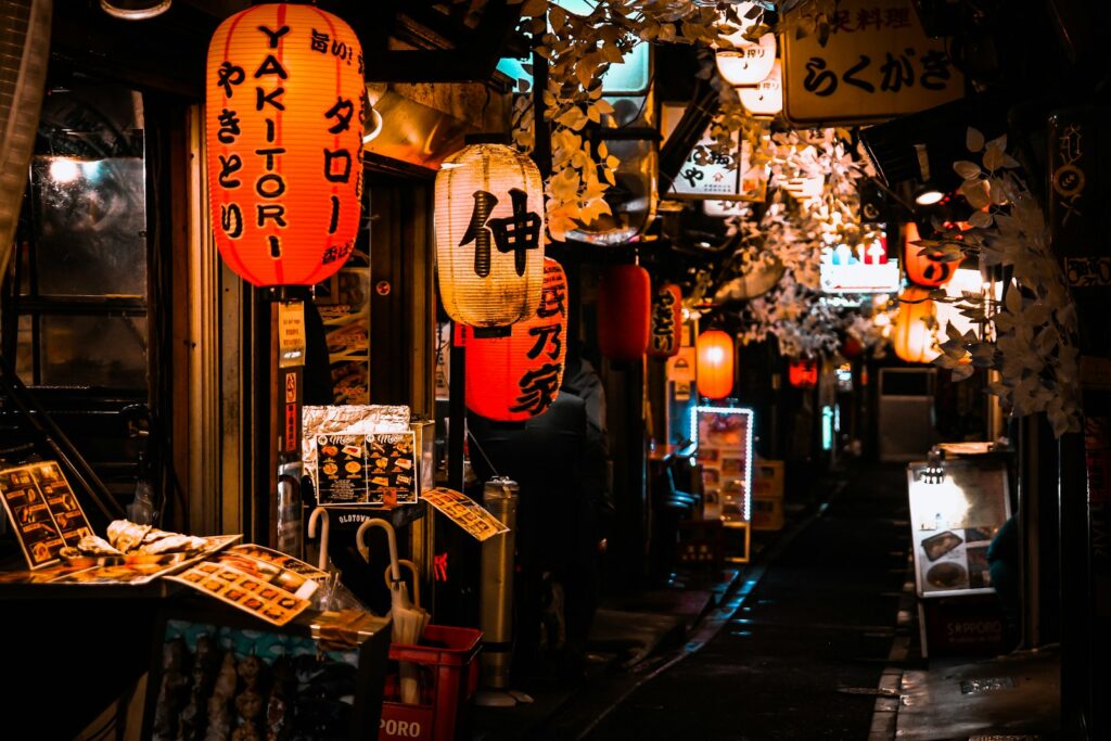 Red paper lanterns hanging in a narrow alley of small restaurants in Shinjuku