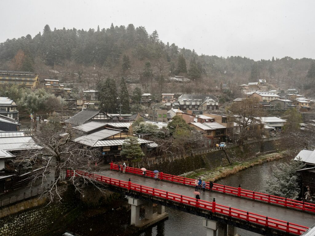 A red bridge over the river in Takayama with the town and hills behind
