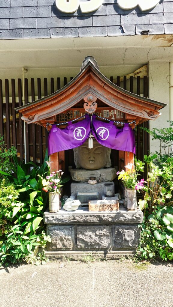 A stone Buddha under a wooden shelter at the Usuki Stone Buddhas
